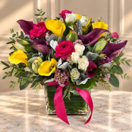 Mixed bouquet with yellow and purple calla lilies in a glass vase