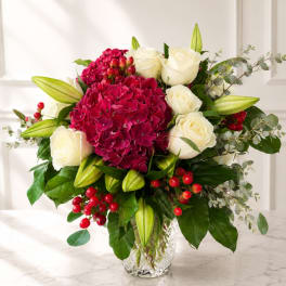 Bouquet of white roses and magenta hydrangeas in a clear glass vase