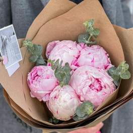 Bouquet of pale pink peonies wrapped in brown paper