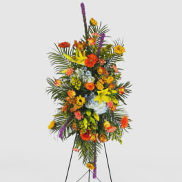 Tall floral standing spray with mixed bright flowers on a black easel