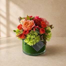 Mixed bouquet of orange and pink roses in a green glass vase