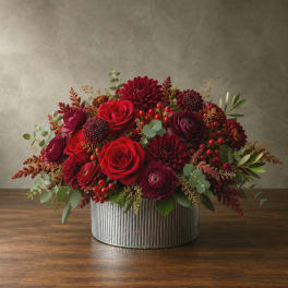 Red and burgundy flower arrangement in a ribbed metal container