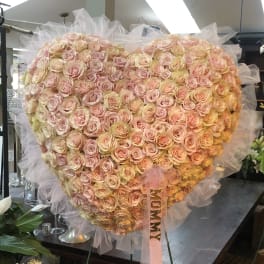 Large heart-shaped bouquet of pale pink roses with a pink ribbon