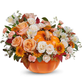 Pumpkin-shaped vase with peach and white flowers and autumn leaves