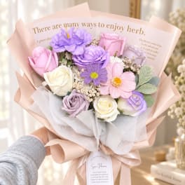 Pastel bouquet of roses and daisy-like flowers wrapped in pink paper