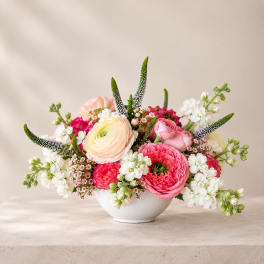 Pink and white mixed flower arrangement in a white bowl vase