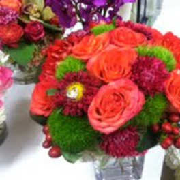 Orange roses and red flowers in a clear vase
