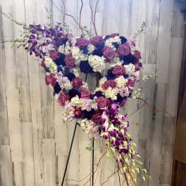 Heart-shaped floral arrangement with purple roses and orchids