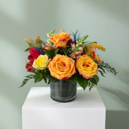 Colorful rose arrangement in a glass vase on a white pedestal