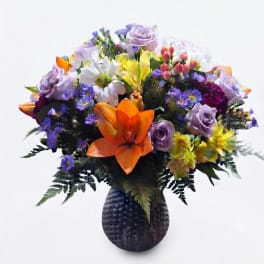 Mixed bouquet of colorful flowers in a dark textured vase