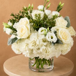 White roses and carnations arranged in a clear glass vase
