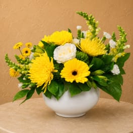Yellow and white flower arrangement in a white bowl vase