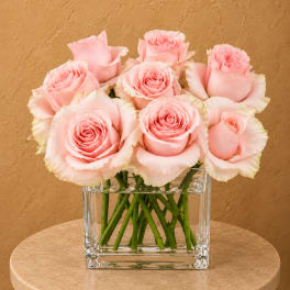 Pink roses arranged in a clear square glass vase
