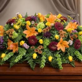 Colorful floral casket spray with orange lilies and yellow blooms