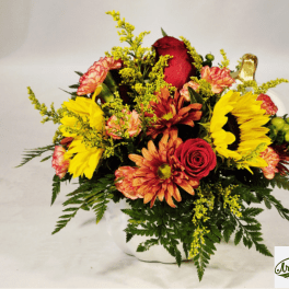 Mixed bouquet with red roses, sunflowers, and orange mums in a white vase