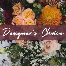 Warm mixed arrangement with peach roses, orange dahlia, burgundy blooms and white filler flowers, Designer's Choice text overlay