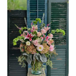 Tall mixed bouquet in a glass vase with pink lilies, roses, hydrangeas, and greenery