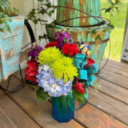 Colorful mixed bouquet in a blue vase with a teal ribbon