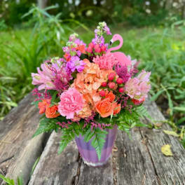 Pink and orange mixed bouquet in a purple vase with a flamingo pick