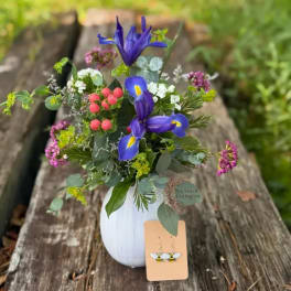Mixed bouquet in a white vase with blue iris and pink berries