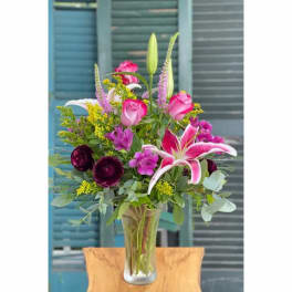 Pink and purple mixed flower arrangement in a clear glass vase