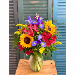Colorful bouquet with sunflowers and purple irises in a glass vase