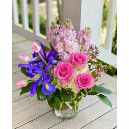 Pink roses and purple irises arranged in a clear glass vase