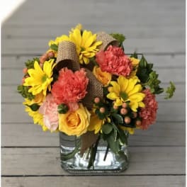 Bouquet of yellow daisies, roses, and carnations in a glass vase