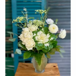 White roses and ranunculus arranged in a textured glass vase