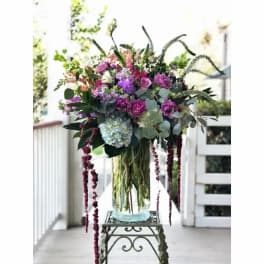 Tall bouquet of purple and pink flowers in a glass vase