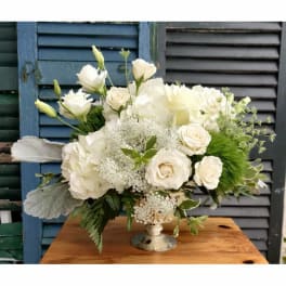White floral arrangement in a silver pedestal vase