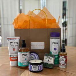 Gift bag with orange tissue paper and assorted Zum bath products