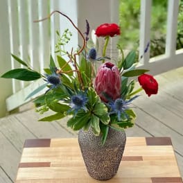 Mixed floral arrangement in a speckled vase with red and blue blooms