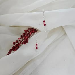 White fabric with red beaded earrings and a red glitter sprig