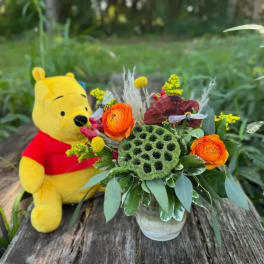 Bouquet in a glass vase beside a Winnie the Pooh plush toy
