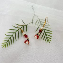 Pair of dangling ladybug earrings on a white textured fabric background
