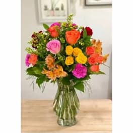 Colorful mixed bouquet of roses and alstroemeria in a clear glass vase
