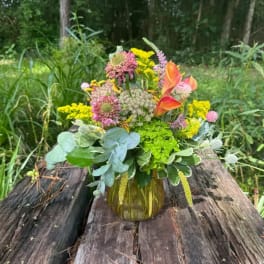 Mixed bouquet in an amber glass vase with orange calla lilies and pink and yellow blooms