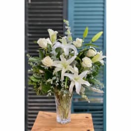 White lilies and roses arranged in a clear glass vase
