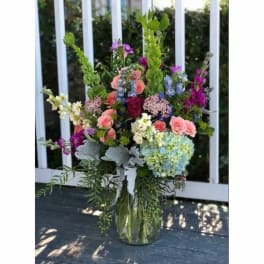 Tall mixed bouquet in a glass vase with pink roses and blue hydrangea
