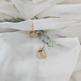 White fabric-wrapped floral accessory with bee earrings and greenery