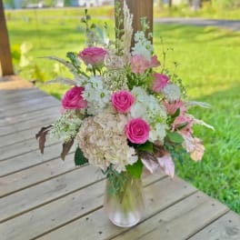 Pink roses and white flowers arranged in a clear glass vase