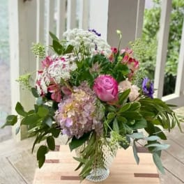 Mixed bouquet with pink roses, hydrangea, and white lace flowers in a glass vase