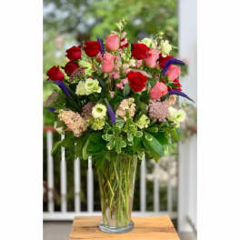 Tall mixed bouquet of red and pink roses in a clear glass vase