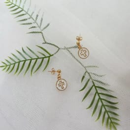 Gold cross earrings on a white textured fabric background