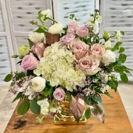 Pink roses and white hydrangeas arranged in a gold vase
