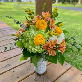 Bouquet of yellow roses, green hydrangeas, and peach alstroemeria in a textured vase