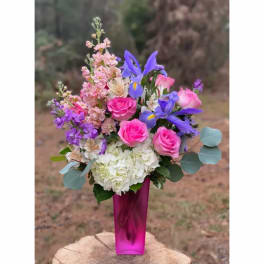 Pink roses and purple flowers in a tall magenta vase