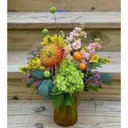 Colorful mixed flower arrangement in an amber glass vase