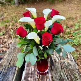 Red roses and white calla lilies arranged in a red vase